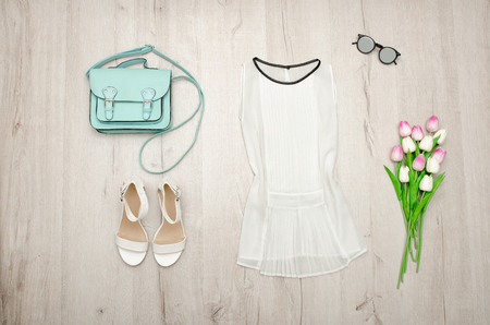 White blouse, glasses, white shoes, handbag and a bouquet of tulips. Fashionable concept. Wooden background.の写真素材