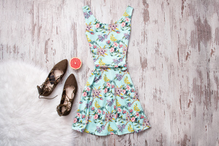 Blue dress in flowers and brown shoes. Wooden background, fashionable conceptの写真素材