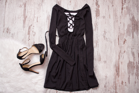 Black dress with long sleeves and a binder, black shoes. Wooden background, fashionable conceptの写真素材