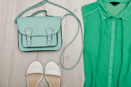 Part of a green blouse, white shoes, handbag. Fashionable concept. Wooden backgroundの写真素材