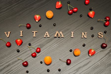 Fruits and inscription vitamins on a black wooden background, food conceptの写真素材