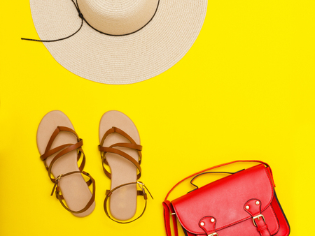 Fashionable concept. Women's beach hat, red handbag, sandals. Yellow background, top viewの写真素材