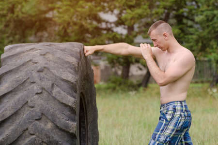 Young man boxing with the tire. Workoutの写真素材