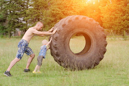 Dad and son push a big tire. street workoutの写真素材