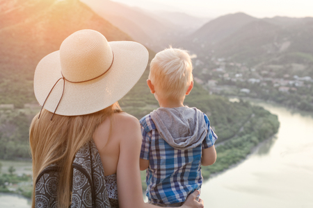 Mom and son are looking at the river and the city in the distance. Back viewの写真素材