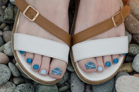 Female feet in sandals, pebbles, close-upの写真素材