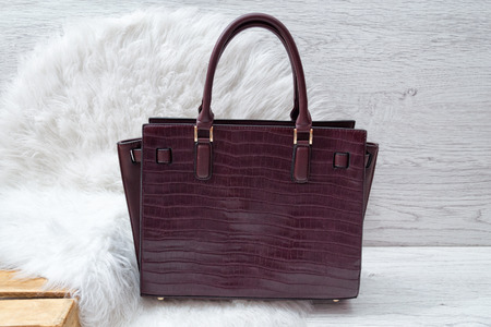 Dark purple bag on white fur. Fashionable conceptの写真素材