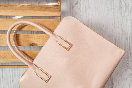 Beige female bag on white fur. Fashionable concept, top viewの写真素材