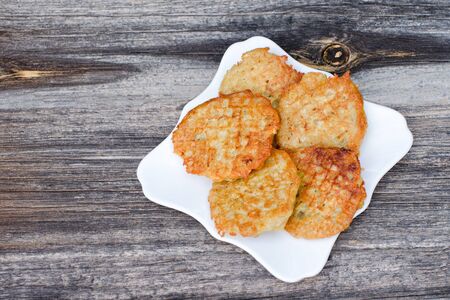 Plate with potato pancakes, gray wood background, top view
