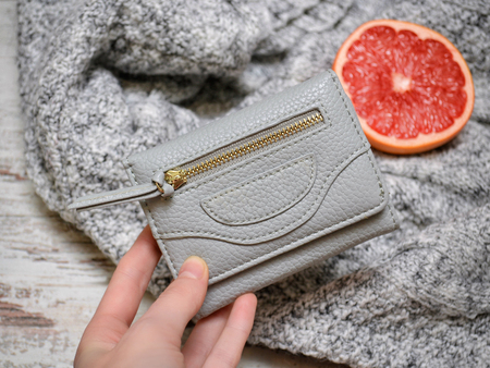 Fashion concept. Small gray purse in a female hand on a background of a sweaterの写真素材