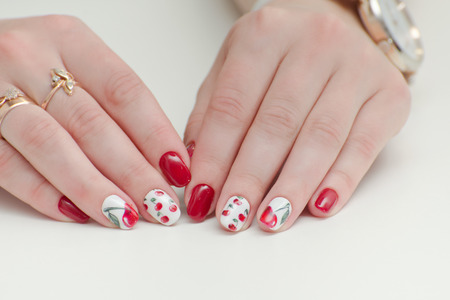 Female hands with manicure, red nail polish, drawing with cherries. White background.の写真素材