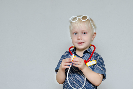 Little boy playing doctor. Toy glasses and phonendoscope. Portraitの写真素材