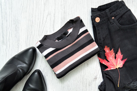 Striped sweater, black jeans, boots and red maple leaf. Fashionable conceptの写真素材