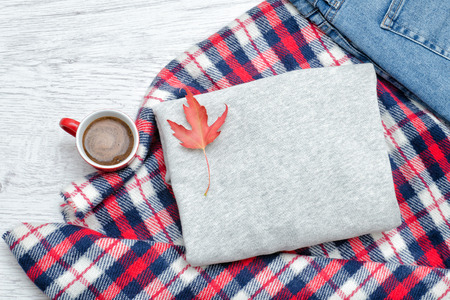 Gray sweater, plaid, jeans, coffee mug and autumn leaves. Fashionable conceptの写真素材