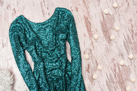 Emerald dress in sequins and garland on a wooden background. Fashionable concept.の写真素材