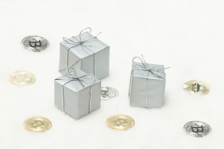 Silvery gift boxes and bitcoins coins on a white backgroundの写真素材