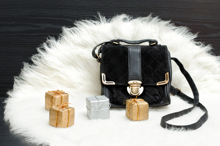 Black bag and gift box on white fur. Fashionable concept. Holiday shoppingの写真素材