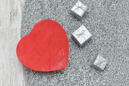Red heart shaped box on a knitted sweater. Silver gift boxes. Fashionable conceptの写真素材