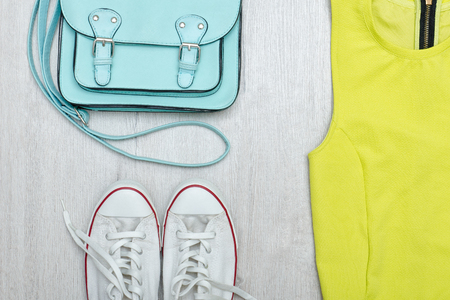 Lime green blouse, white sneakers and handbag. Fashionable concept. Wooden background.の写真素材