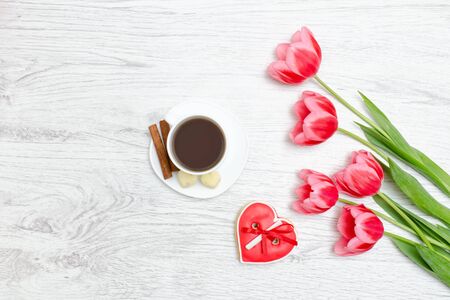 Pink tulips, mug of coffee and red gingerbread. Light wooden background. の写真素材