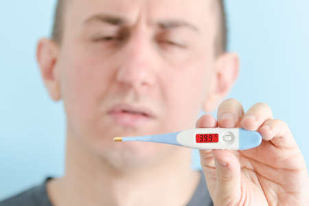 Man with a thermometer in his hand. Increased body temperatureの写真素材