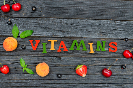 Color inscription Vitamins and fruits. Black wooden background. Food conceptの写真素材