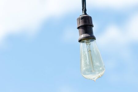 Lonely electric light bulb against the blue sky
