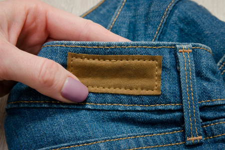 Leather label on jeans in female handの写真素材