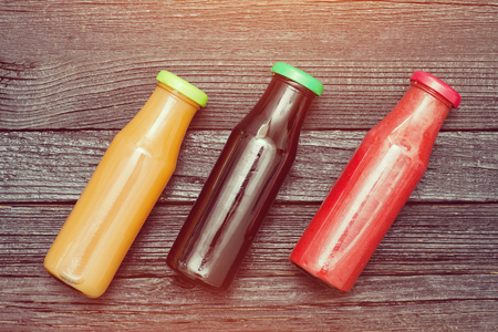 Three bottles of juice on black wooden background. の写真素材