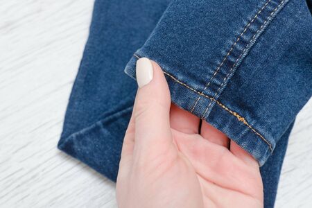Part of blue jeans in female hand. Fashionable concept.