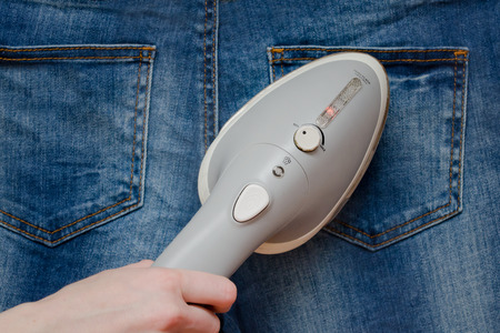Female hand irones a jeans, close-upの写真素材