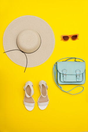 Fashionable concept. Female beach hat, handbag, white shoes. Yellow backgroundの写真素材