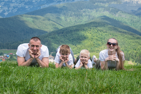 Family with children lies on the grass. Mountains on the background.の写真素材