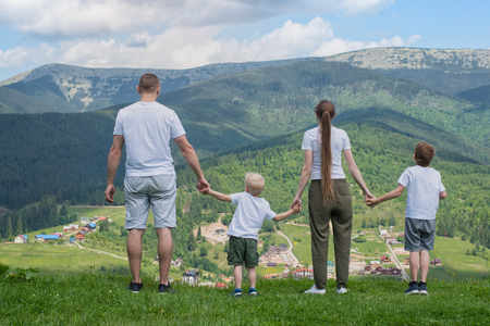 Family holiday. Parents and two sons admire views of the valley. Mountains in the distance. Back viewの写真素材