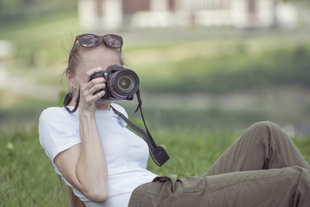 Girl with camera sits on a hill and photographyの写真素材