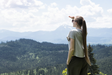 Women is standing and looking into the distance. Forest and mountains in the backgroundの写真素材