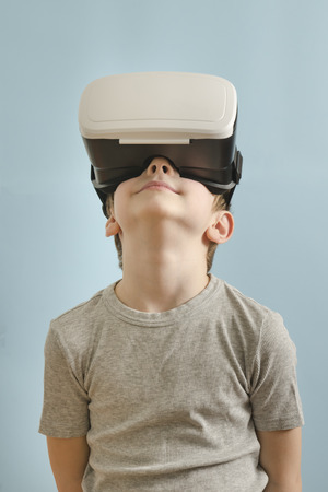 Smile boy with glasses of virtual reality looks up. Blue backgroundの写真素材