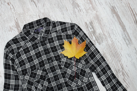 Black checkered shirt and maple leaves. Fashionable concept