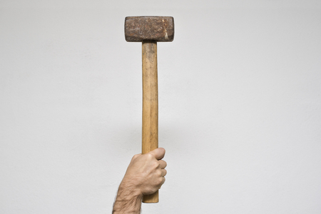 Old sledgehammer in a man's hand. White backgroundの写真素材