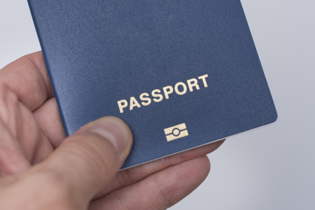 Blue passport with biometrics in a man's hand. White background. Close upの写真素材