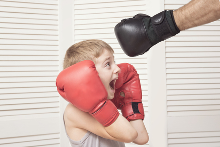 Boy in boxing gloves fights with a man's hand in a glove.の写真素材