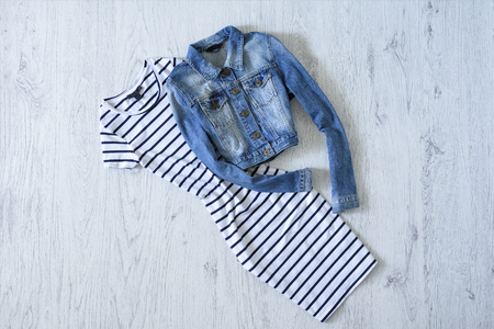 Striped dress and denim jacket on wooden background. Fashionable conceptの写真素材