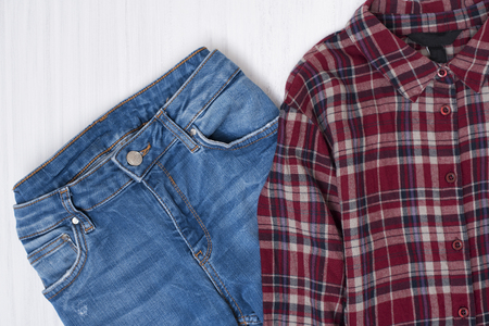 Blue jeans and red checkered shirt on wooden background. Fashionable conceptの写真素材