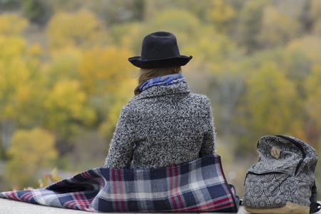 Woman are sitting on a hill. Autumn. Forest in the distance. Back viewの写真素材