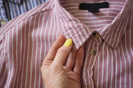 Collar of a pink shirt in female hand. Fashionable conceptの写真素材
