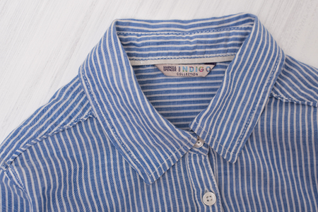 KHARKOV, UKRAINE- OCTOBER 1, 2018: Collar of blue striped shirt on wooden background. Indigo collectionのeditorial素材