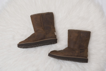 Winter brown boots on white fur. Fashion concept