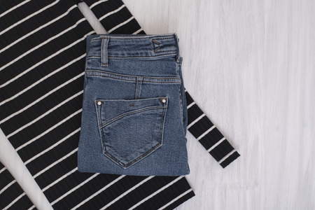 Blue jeans and black striped sweater on wooden background. Fashionable conceptの写真素材