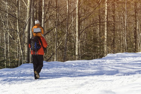 Man with son on shoulders walking along the road in a snowy forest. Winter. Dayの写真素材