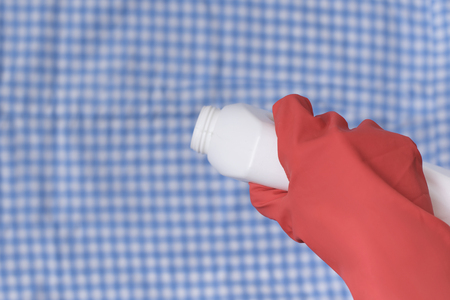 Hand in glove pours liquid for washing on clothes. Close-upの写真素材